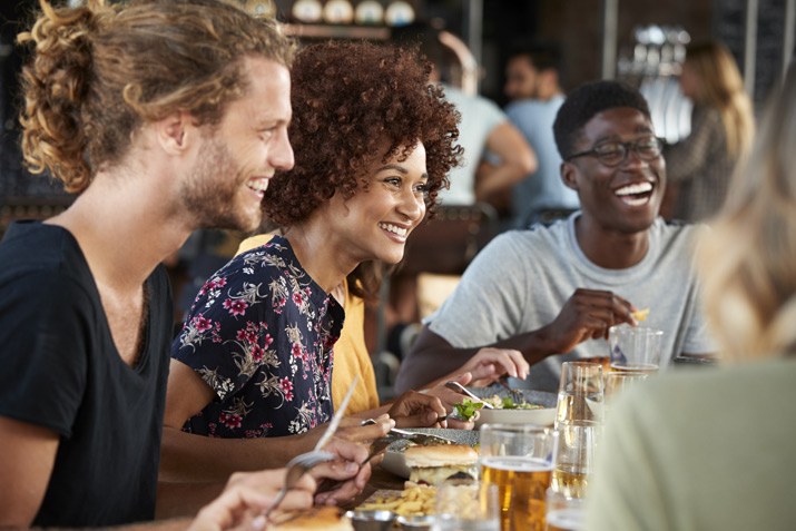 Group Of Young Friends Meeting For Drinks And Food In Restaurant