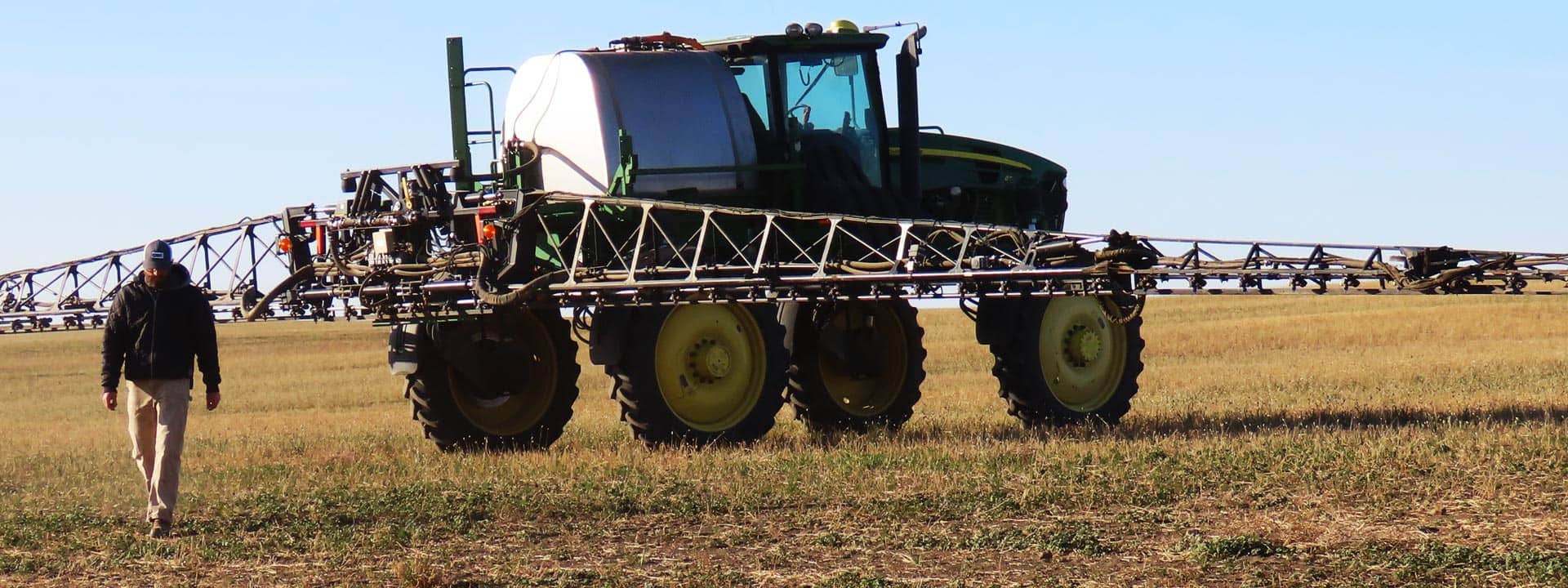 Man walking in front of crop sprayer