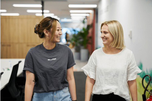 Two woman walking down a hallway, smiling
